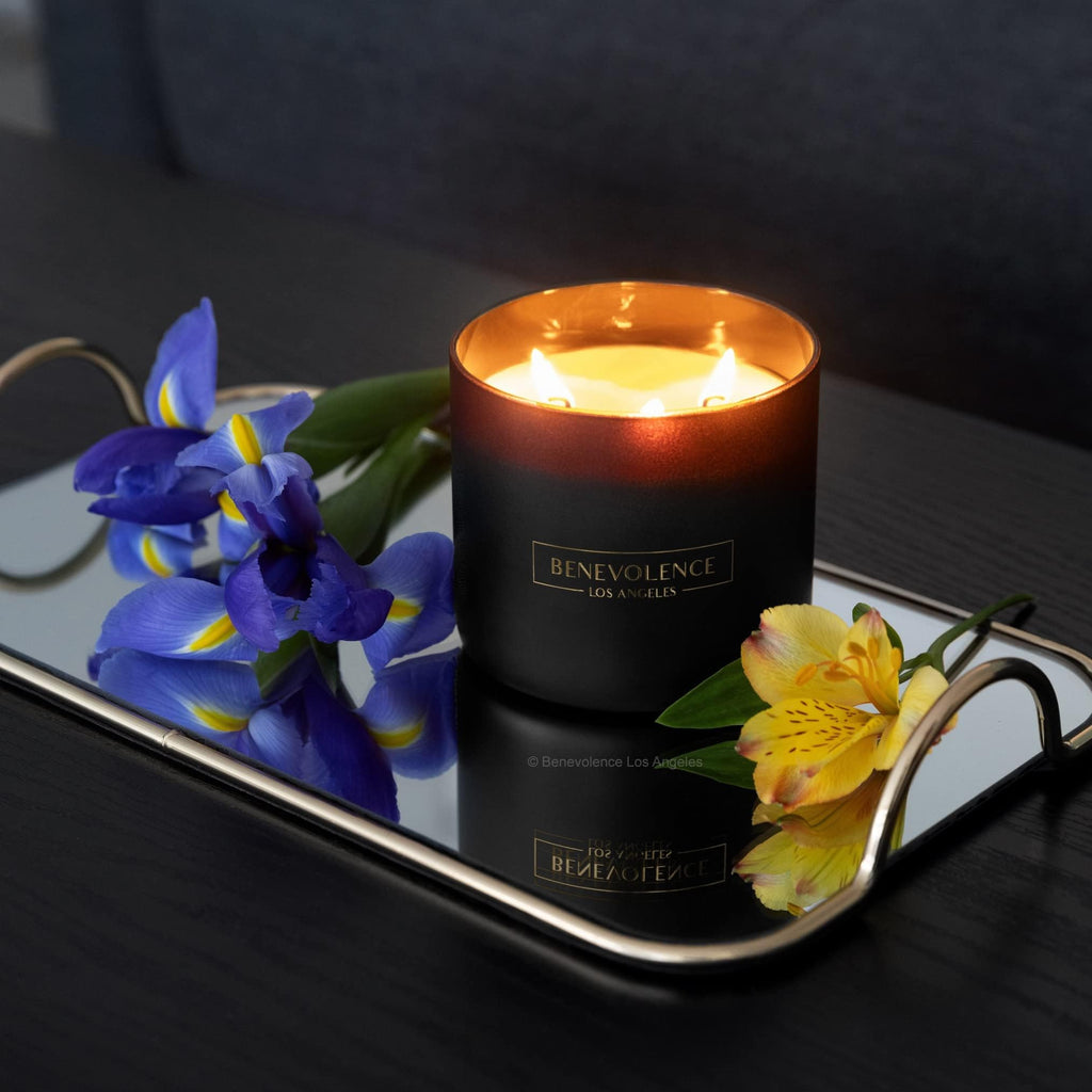 Candle in a decorative holder with flowers on a reflective surface