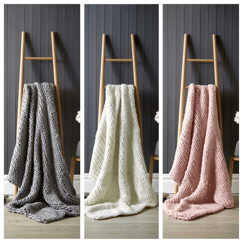 Cream, Grey, Pink chunky knit throw draped over a wooden ladder in a calm neutral interior.